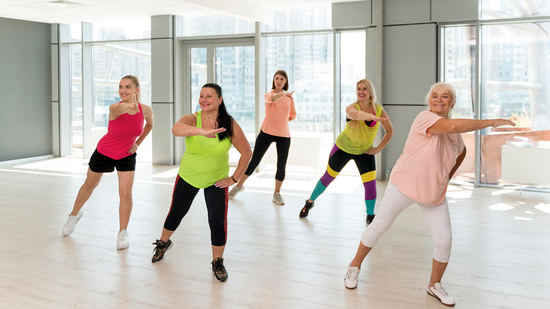 Ομάδα ανθρώπων απολαμβάνει μάθημα zumba σε στούντιο, συνδυάζοντας χορό και γυμναστική με ενέργεια και χαμόγελα.